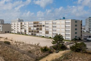A multi-story hotel with a flat facade, balconies, and a sandy area in front. - Beautiful two bedroom, 2 bath condo in desirable North OC with great views! (Ocean City)