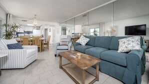 A modern living room with a sofa, armchair, and coffee table. There is a dining area with a table and chairs in the background. - Beautiful two bedroom, 2 bath condo in desirable North OC with great views! (Ocean City)