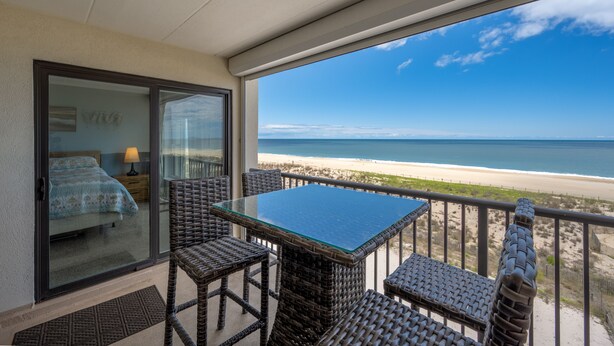A balcony with wicker furniture, a glass table, and a view of the beach. - Beautiful two bedroom, 2 bath condo in desirable North OC with great views! (Ocean City)