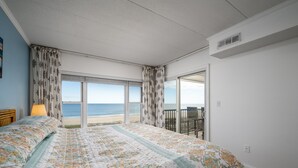 A bedroom with a large bed, a view of the beach, and a balcony with a chair. - Beautiful two bedroom, 2 bath condo in desirable North OC with great views! (Ocean City)