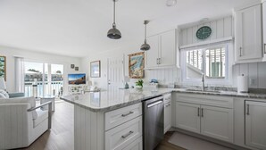 A modern kitchen with white cabinetry, a central island, pendant lighting, and a view of the outdoors.