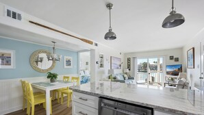 A modern kitchen with a white countertop, yellow chairs, and a built-in dishwasher.