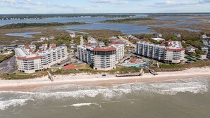 A coastal hotel with multiple buildings, a beach, and a view of the sea and marshy landscape.