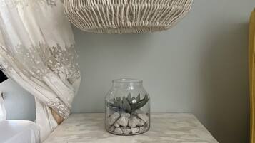 A small, rustic bedside table with a glass jar containing rocks and a succulent plant.