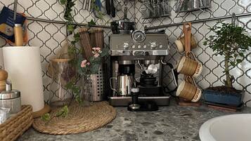 Una cocina con cafetera, utensilios colgados y una planta en maceta.