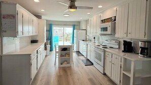 Une cuisine moderne avec des armoires blanches, un ventilateur de plafond et une vue sur l’extérieur.