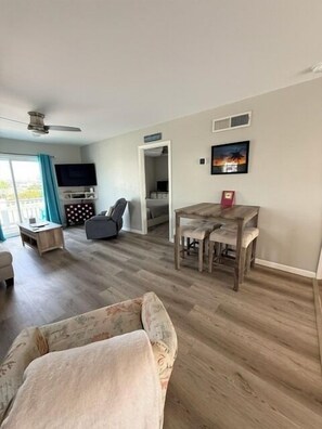 A living room with a sofa, a dining table, and a TV.