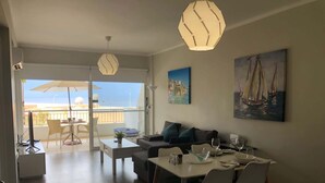 Una sala de estar moderna con comedor, un sofá, una mesa de centro y un cuadro de veleros.