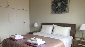 Habitación de hotel con una cama grande, dos mesitas de noche, un armario y un adorno en la pared.