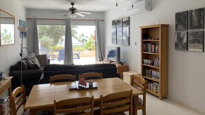 Un salon comprenant une table à manger, des chaises, un canapé, des ventilateurs de plafond, une bibliothèque et un téléviseur.