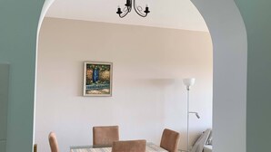 Ein Essbereich mit Tisch, Stühlen, einer Chandelüster und einem gerahmten Bild an der Wand.