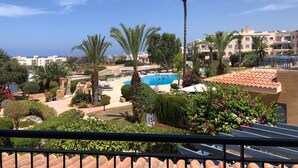 Un complexe hôtelier doté d’une piscine, de palmiers et offrant une vue sur la mer.