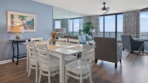 Ein modernes Wohnzimmer mit Essbereich, großen Fenstern und einem Balkon.