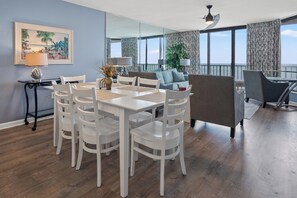 A modern living room with a dining area, large windows, and a balcony.