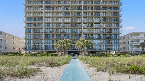 Ein mehrstöckiges Hotel mit Innenhof, Balkonen in jeder Etage und einem Sandweg zum Eingang.
