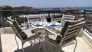 A balcony with a table set for two, overlooking a coastal view. - Kings Palace - Modern Penthouse | Incredible Sea Views | Pool (Paphos)