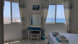 A bedroom with a bed, a dresser, a mirror, and a view of the sea. - Kings Palace - Modern Penthouse | Incredible Sea Views | Pool (Paphos)