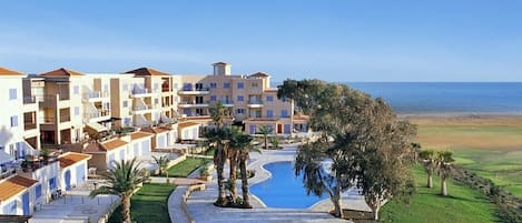 A resort with multiple buildings, a swimming pool, and a view of the sea.