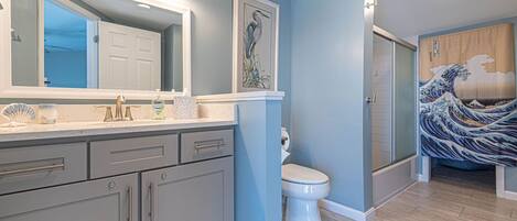 A bathroom with a large mirror, a toilet, a shower, and a sink with a vanity.