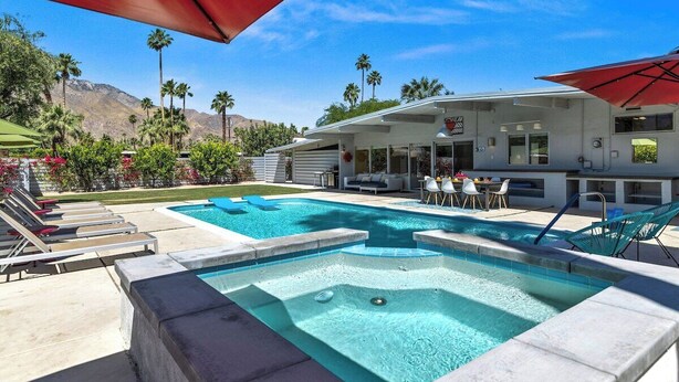 Un espace piscine comprenant des chaises longues, un jacuzzi et un coin salon abrité.