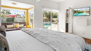 Une chambre avec un grand lit, une télévision et une vue sur une piscine.