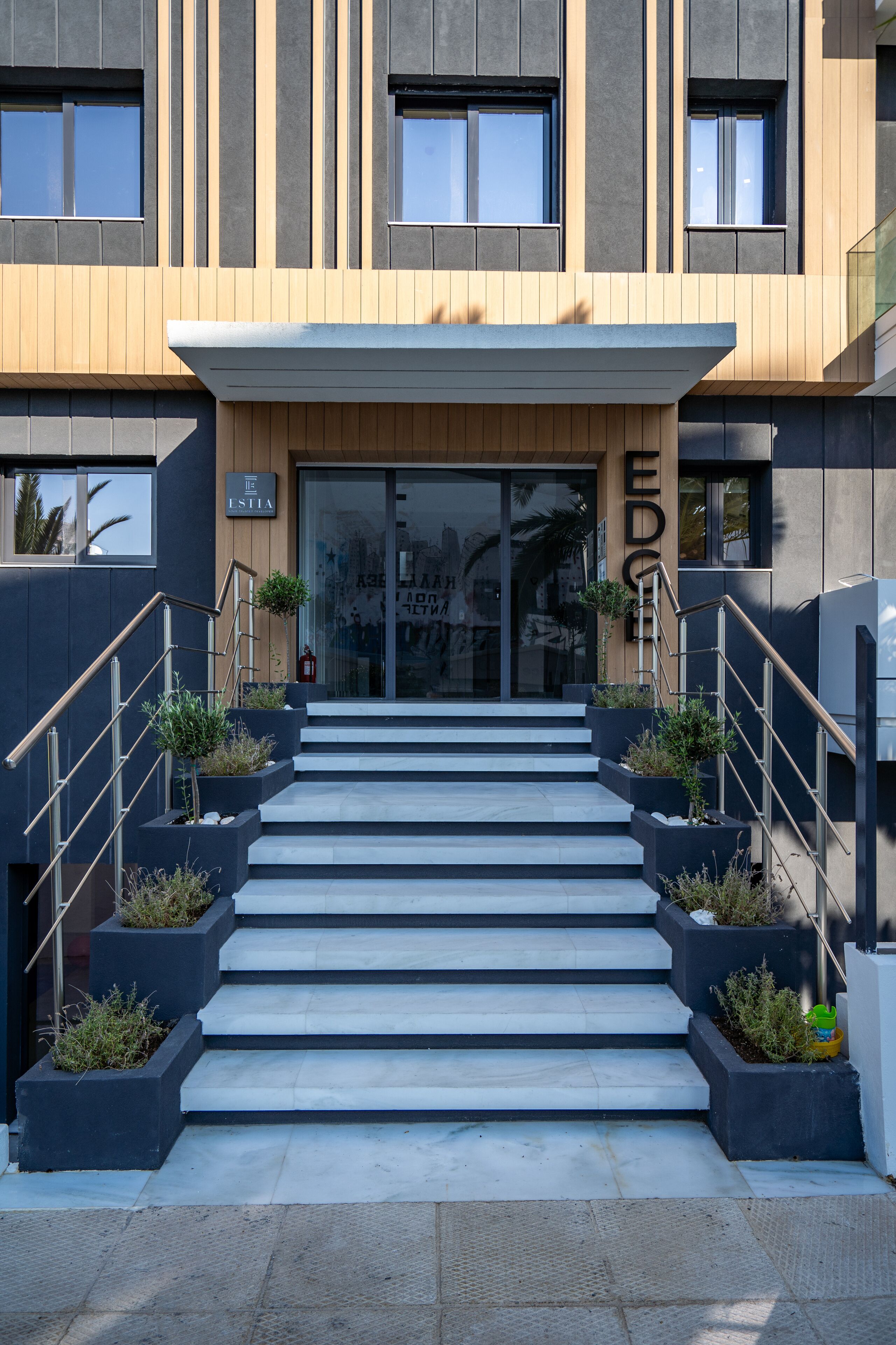 A modern building with a staircase leading to a glass entrance.