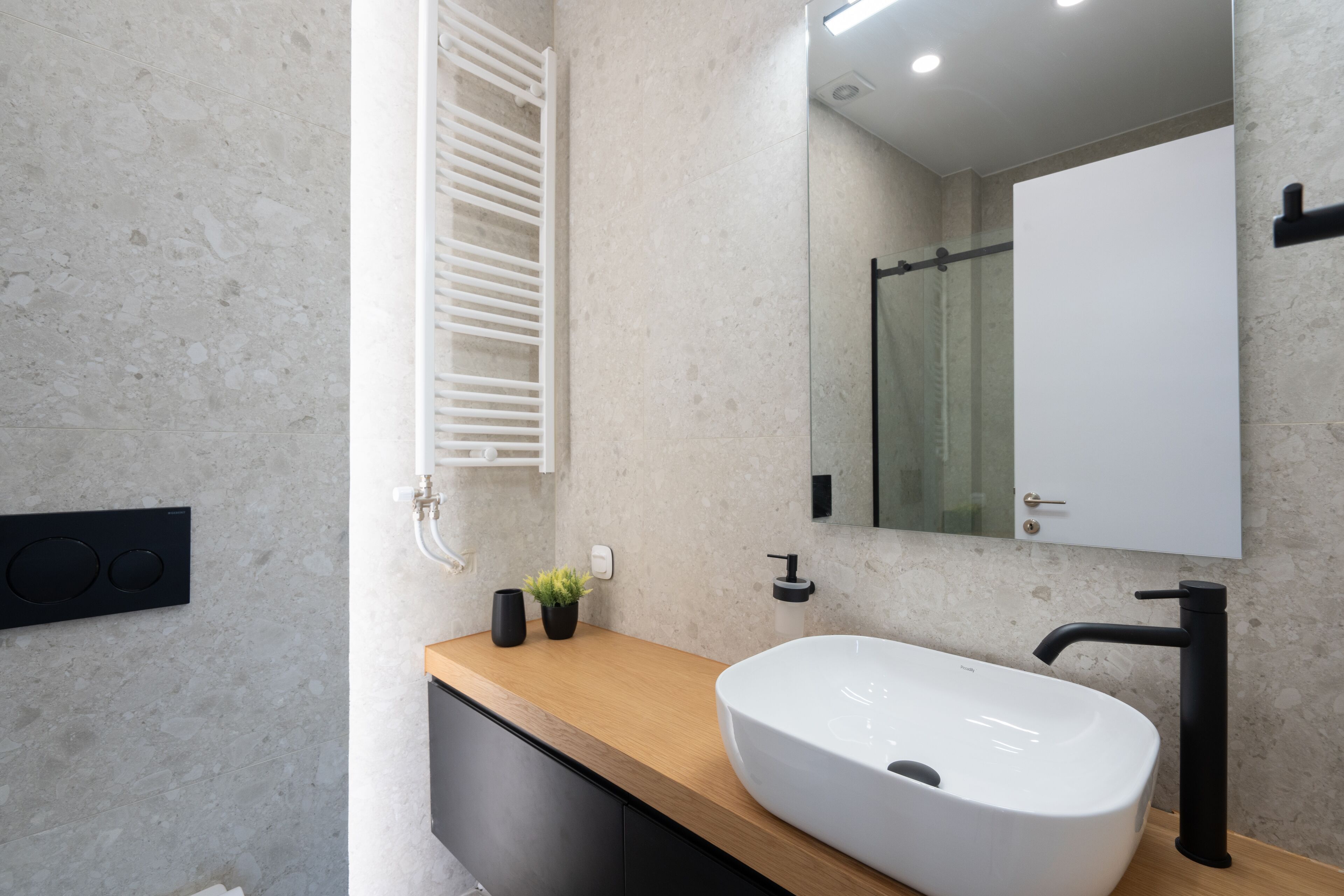 A modern bathroom with a large white sink, black faucet, and a wooden countertop.