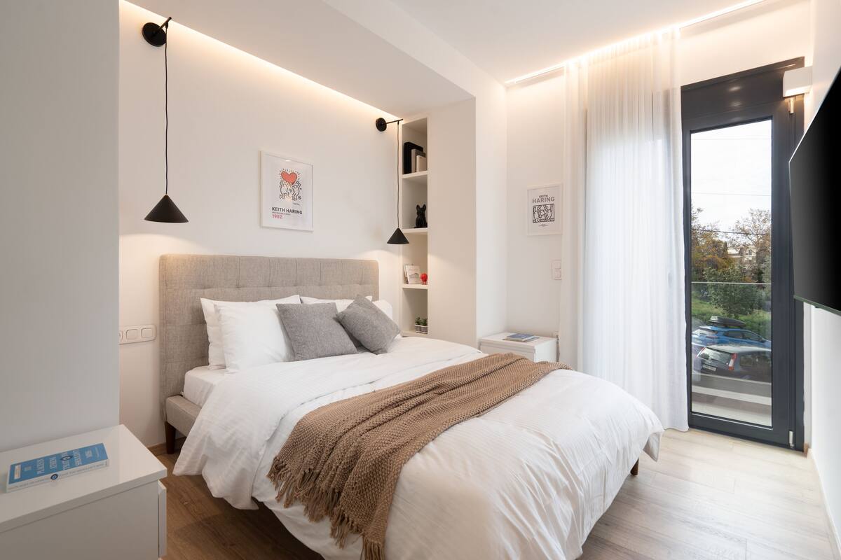 Une chambre moderne avec un grand lit, des tables de chevet, une armoire et une vue sur l’extérieur grâce à une porte vitrée.