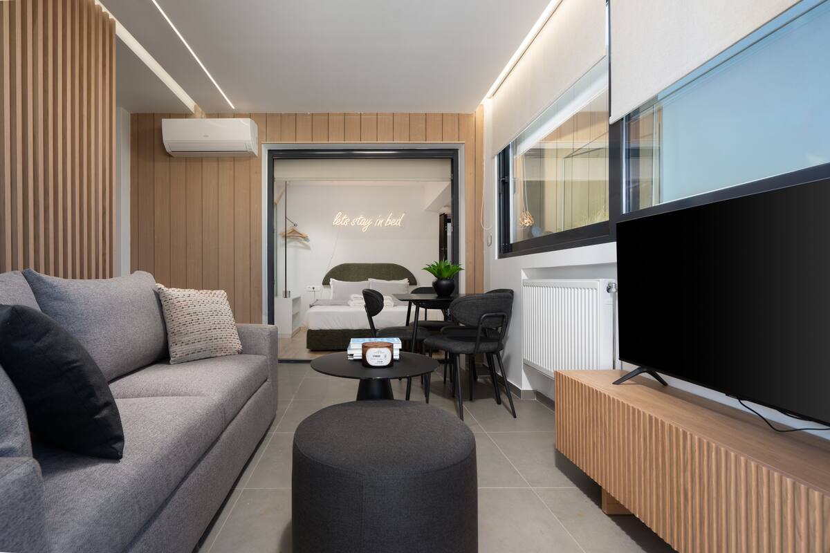 Un salon moderne comprenant un canapé, une table basse, un téléviseur et un petit coin repas.