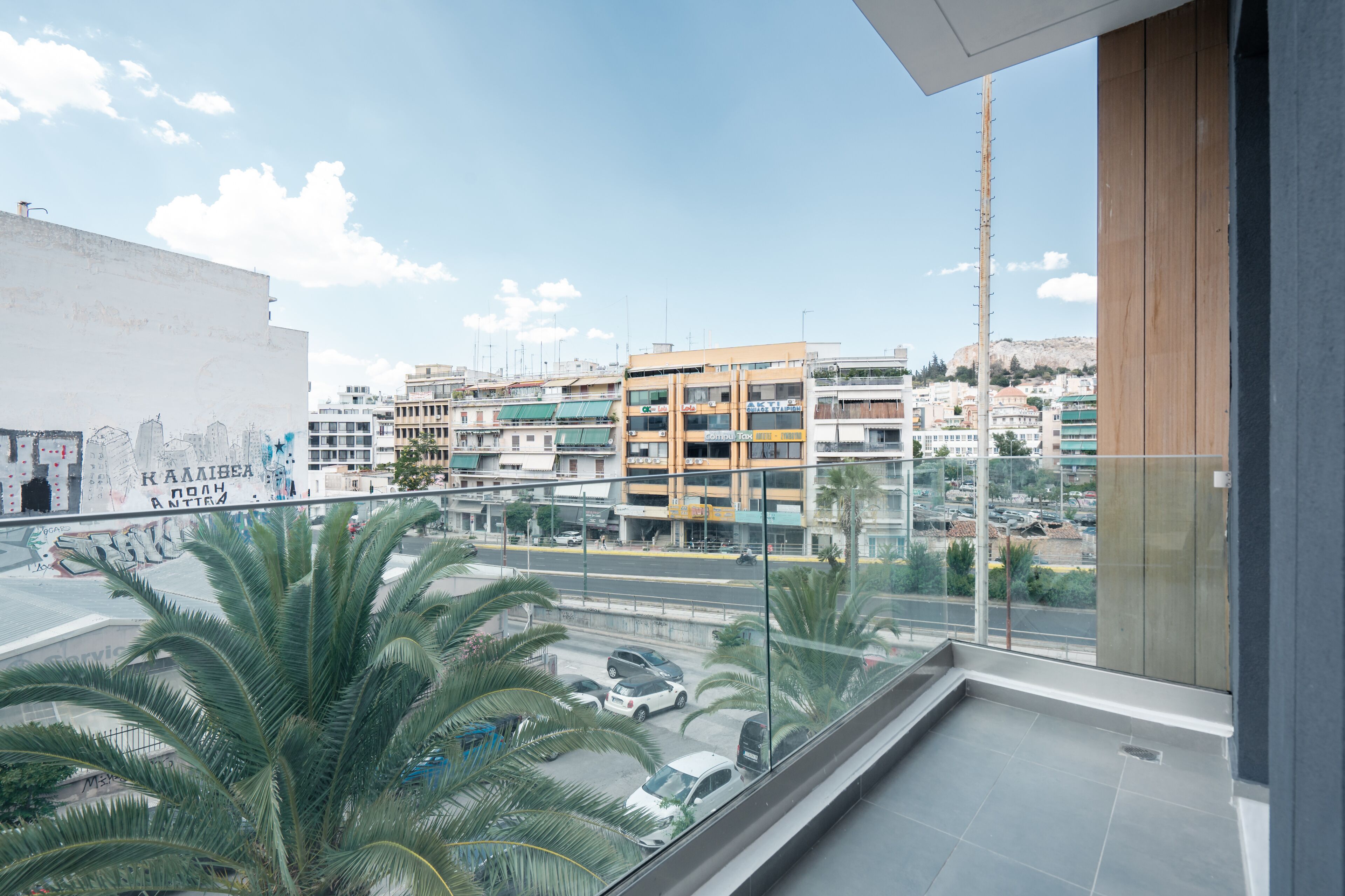Un balcon offrant une vue sur le paysage urbain, avec des bâtiments et des palmiers.