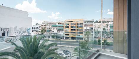 Un balcon offrant une vue sur le paysage urbain, avec des bâtiments et des palmiers.