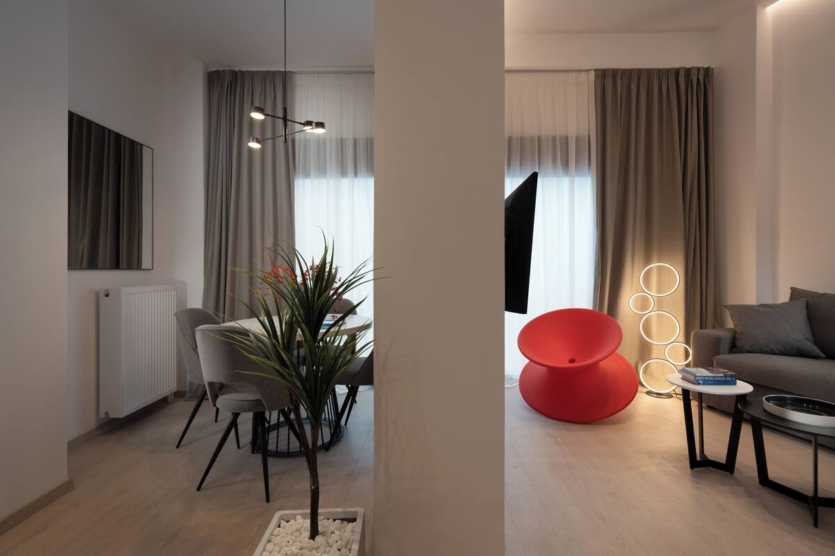 Un salon moderne avec un coin repas, un fauteuil rouge et un canapé.