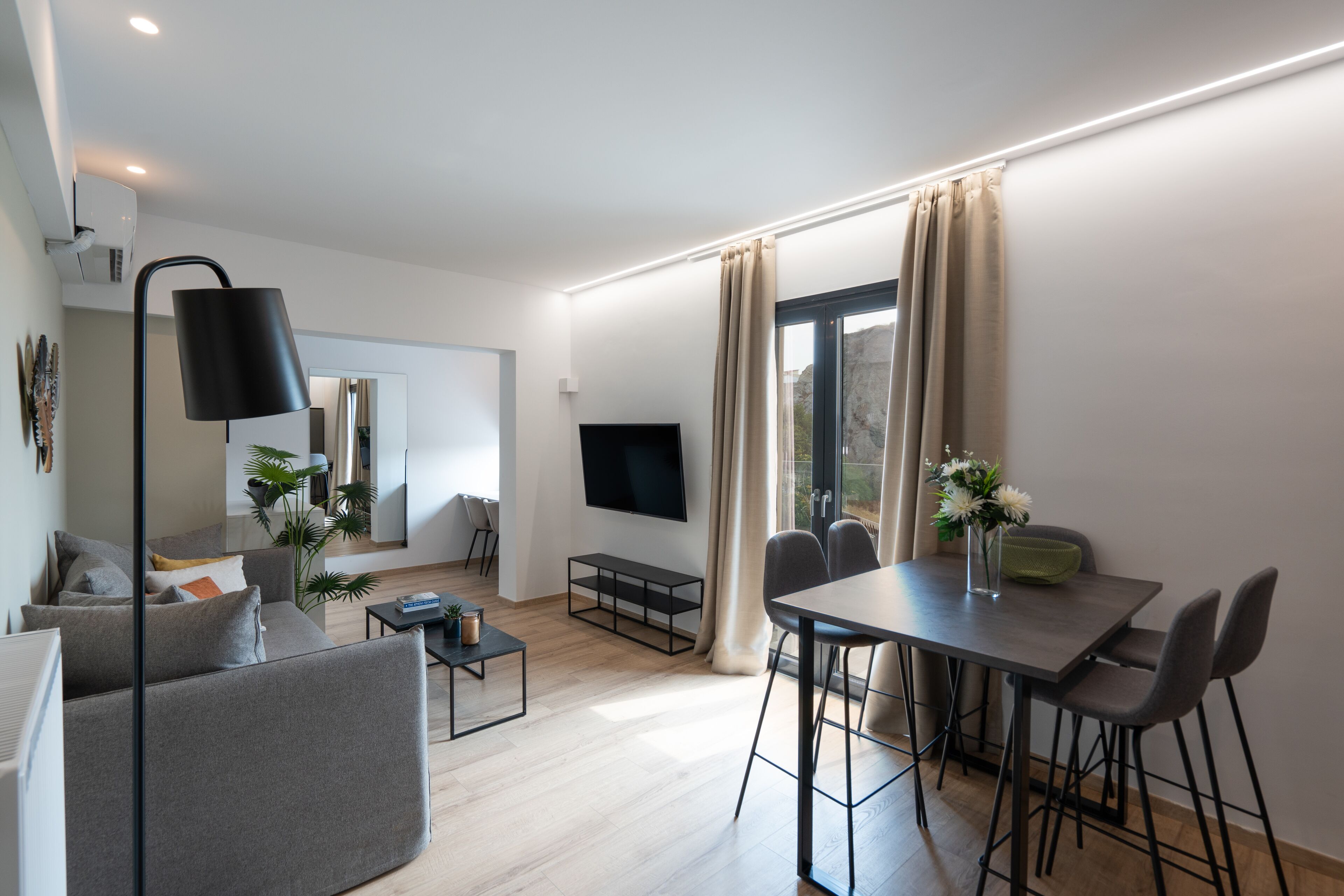 A modern living room with a sofa, coffee table, and dining area with chairs.