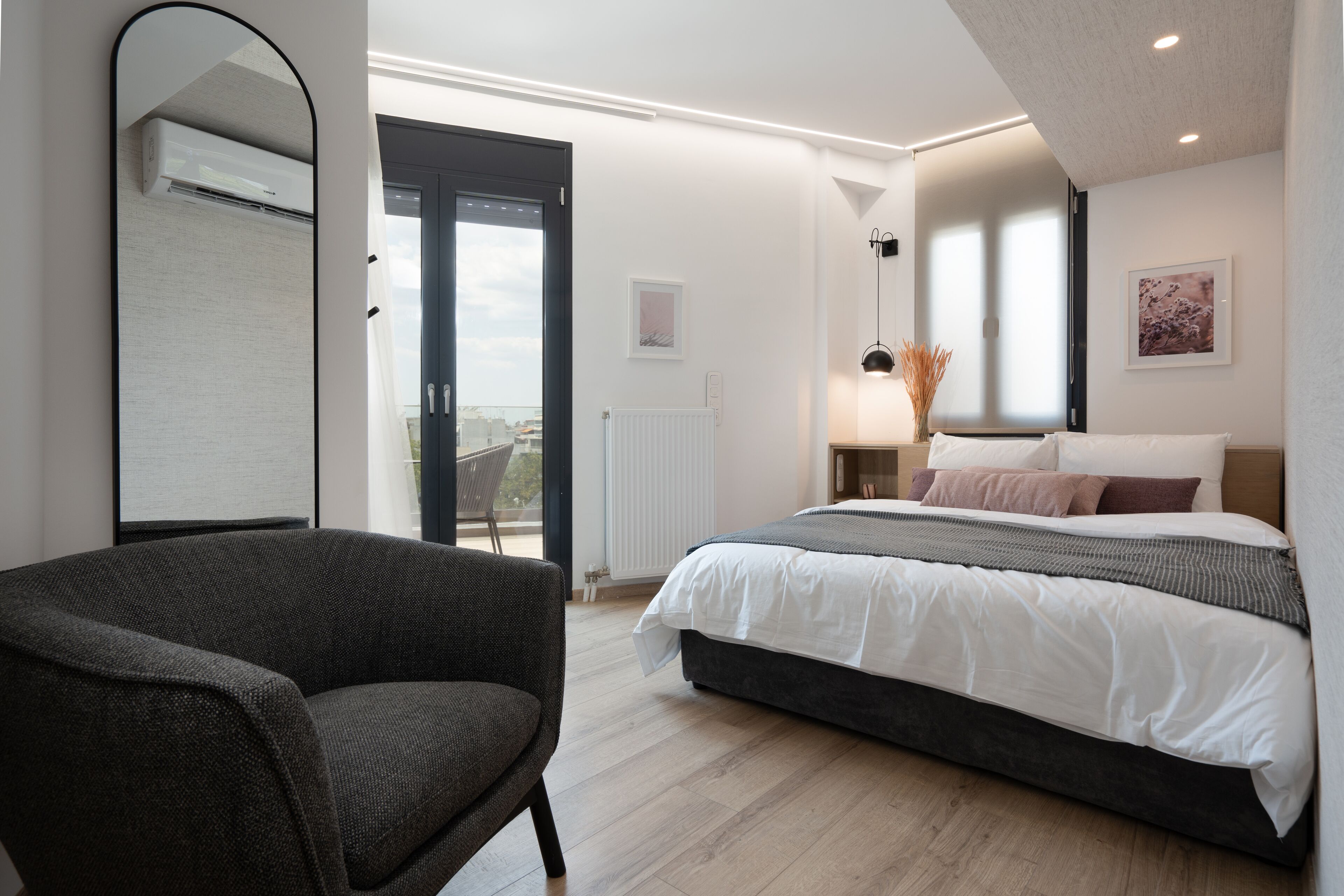 Una camera da letto moderna con un letto grande, una sedia, uno specchio e vista sull'esterno.