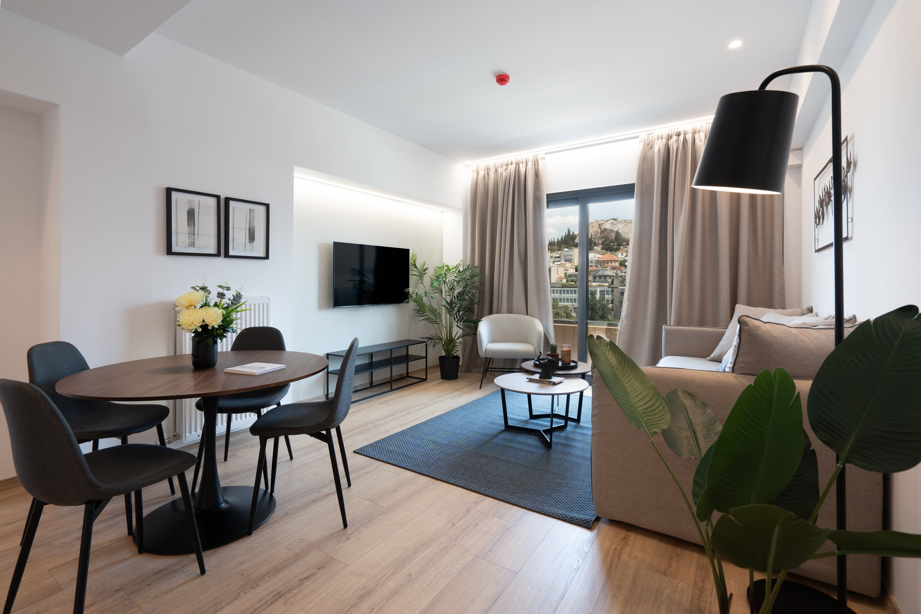 Ein modernes Wohnzimmer mit Essbereich, einer Couch, einem Fernseher und Blick auf die Stadt.