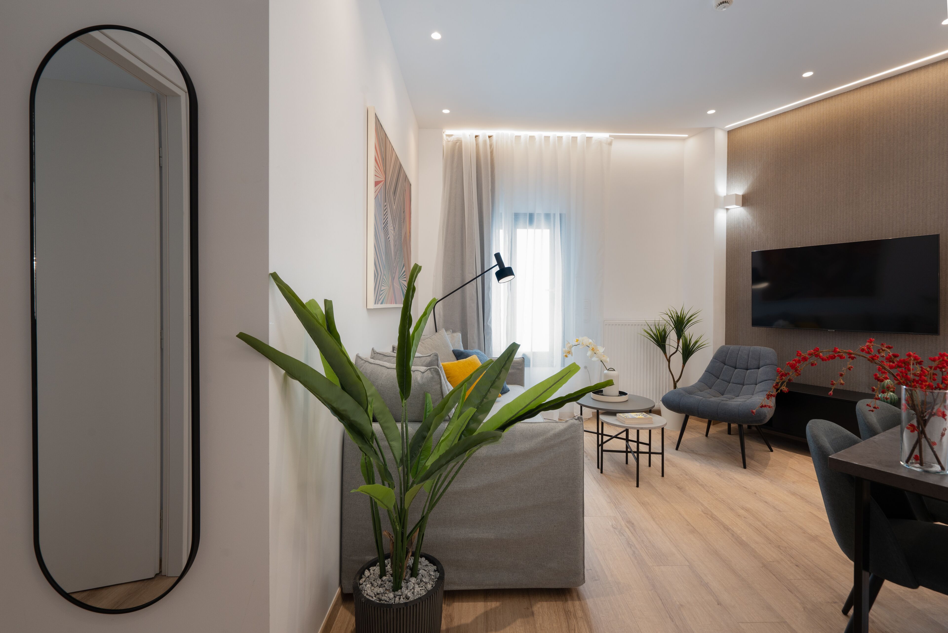 A modern living room with a sofa, a coffee table, a TV, and a plant.