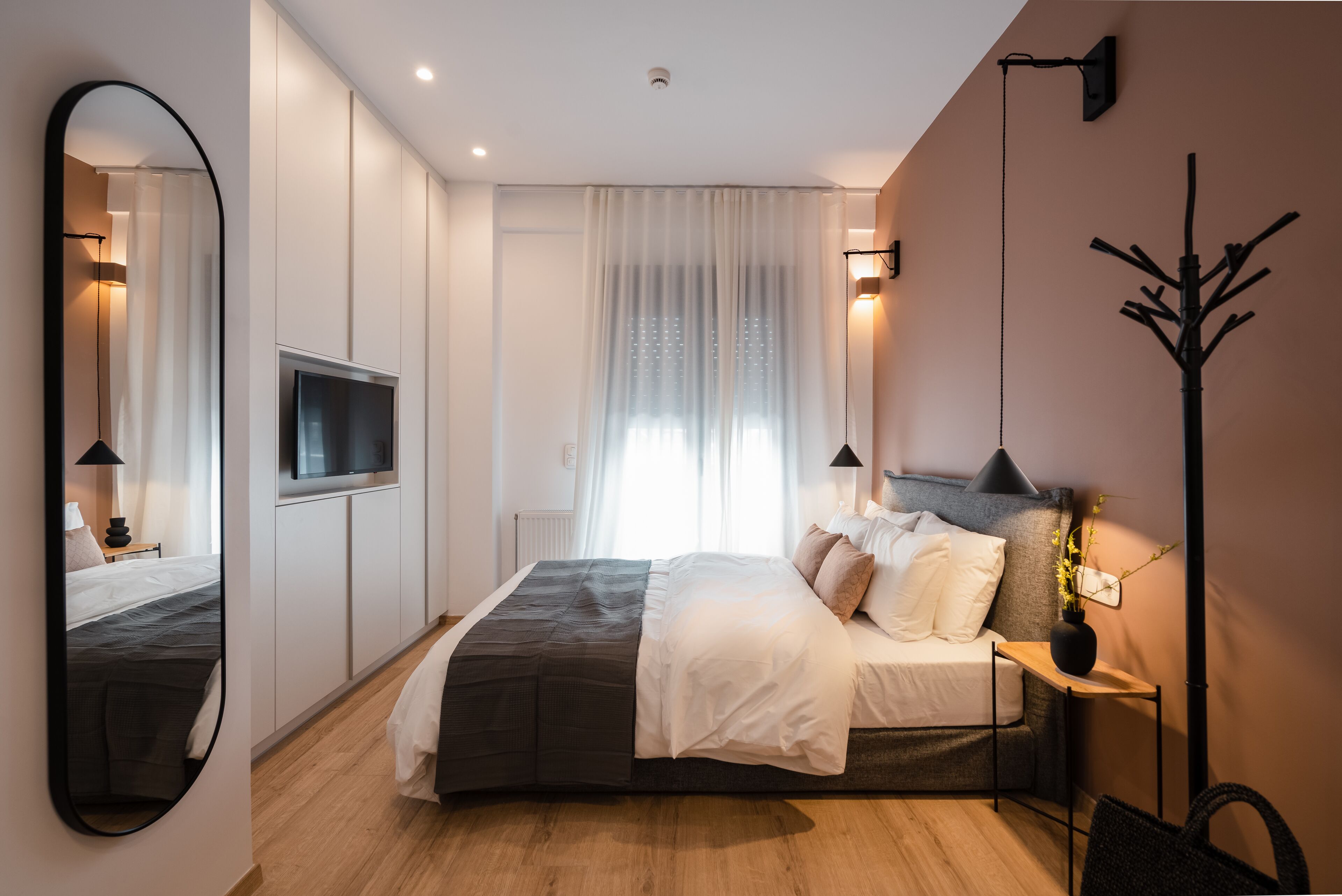 Une chambre à coucher moderne avec un lit, une télévision, un miroir et une table de chevet.