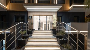 Entrada d'un edifici modern amb escala, portes de vidre i senyalització il·luminada.