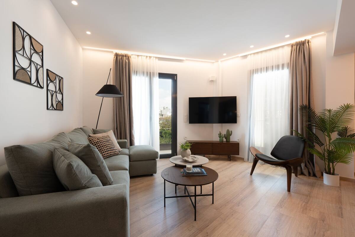 Un salon moderne comprenant un canapé, un fauteuil, une table basse et un téléviseur à écran plat.