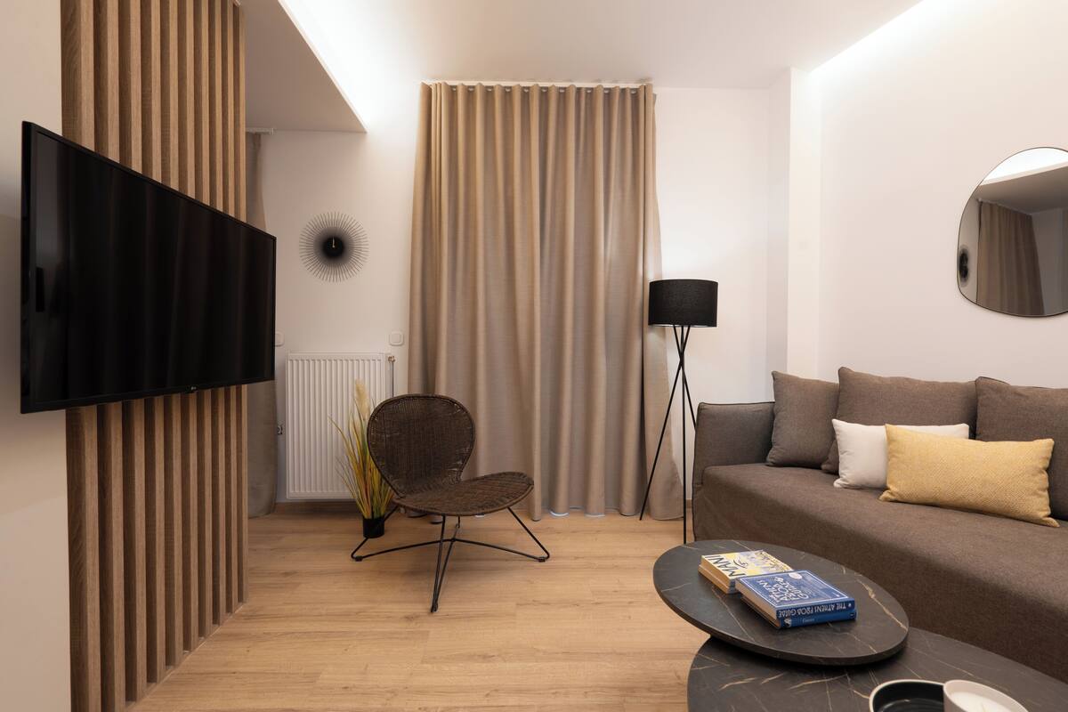 Un salon moderne comprenant un téléviseur à écran plat, un canapé, un fauteuil, une table basse et un lampadaire.