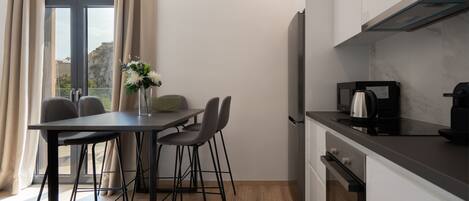 A modern kitchen with a dining area, including a table with chairs, a vase with flowers, and a coffee maker.