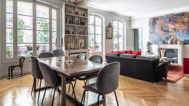 Un salon spacieux avec un coin repas, de grandes fenêtres et une cheminée.