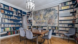 Une bibliothèque avec des étagères, une table en bois et des chaises.