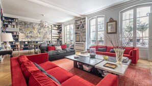 Un salon spacieux avec des canapés rouges, une table basse et une bibliothèque remplie de livres.