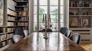 Une pièce avec une table en bois, des étagères et un chandelier décoratif.