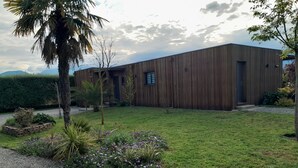 Un bâtiment moderne doté d’une façade en bois, d’une pelouse bien entretenue et d’une variété de plantes et d’arbustes.