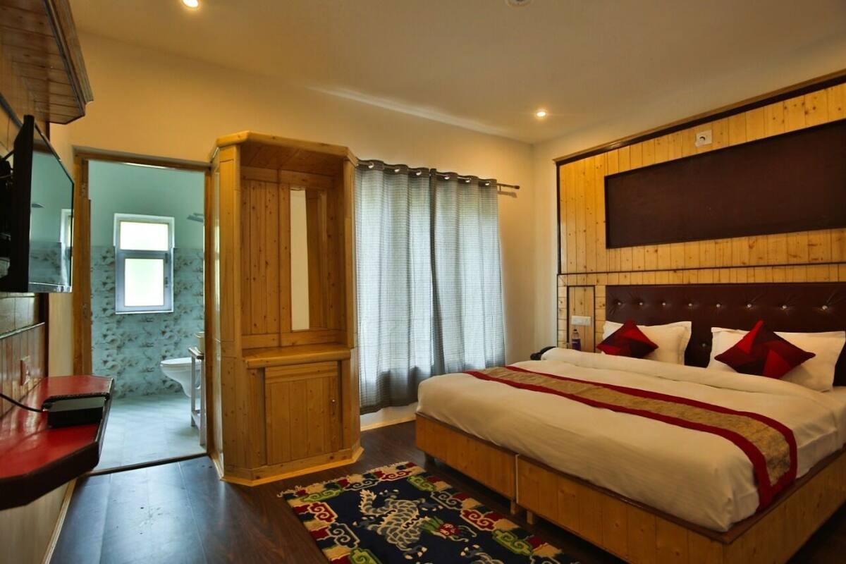 A bedroom with a large bed, wooden headboard, and a red and white bedspread.