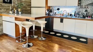 Una cocina moderna con una isla central, taburetes de bar y un salpicadero de piedra.