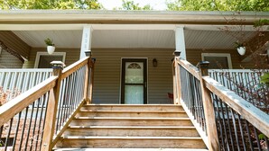 A wooden staircase leading to a house's front door with a porch.
