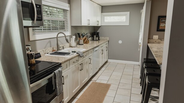 A modern kitchen with stainless steel appliances, white cabinets, and a granite countertop.